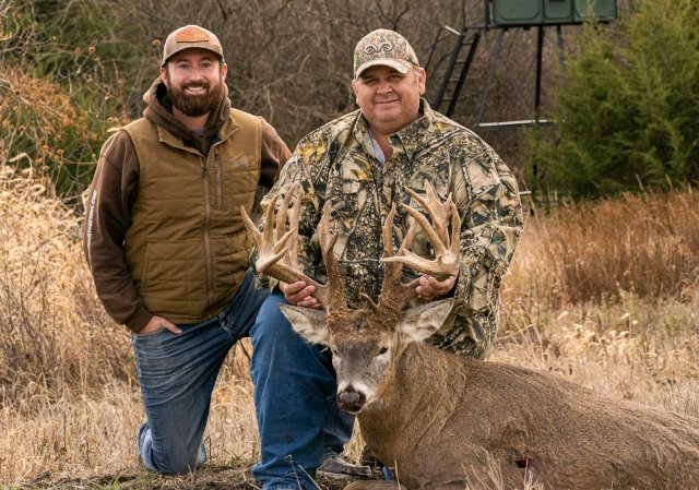 A hunter with his buddy and a giant deer.