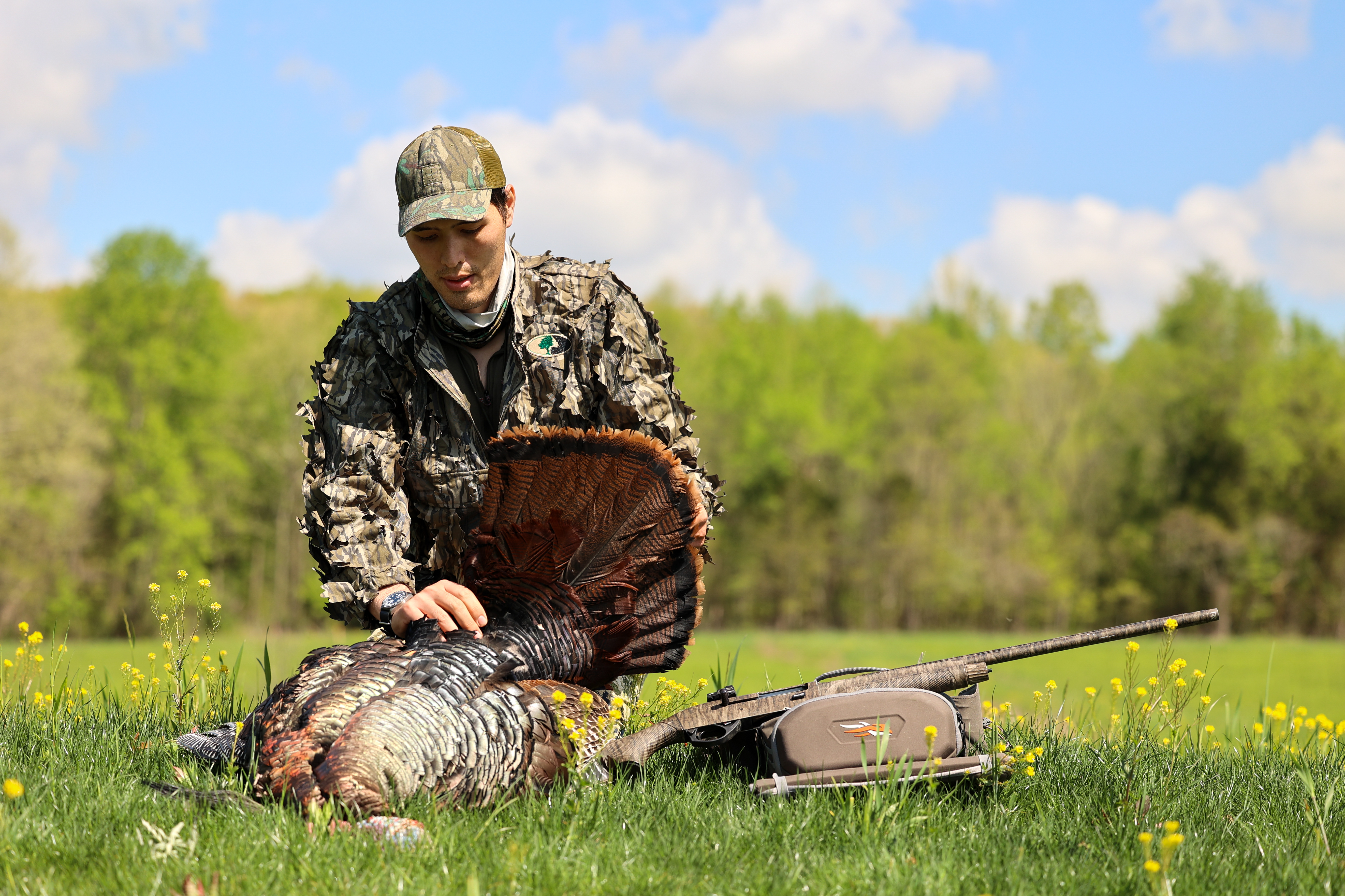 A hunter dressed in camo admires a big gobbler he just harvested. 