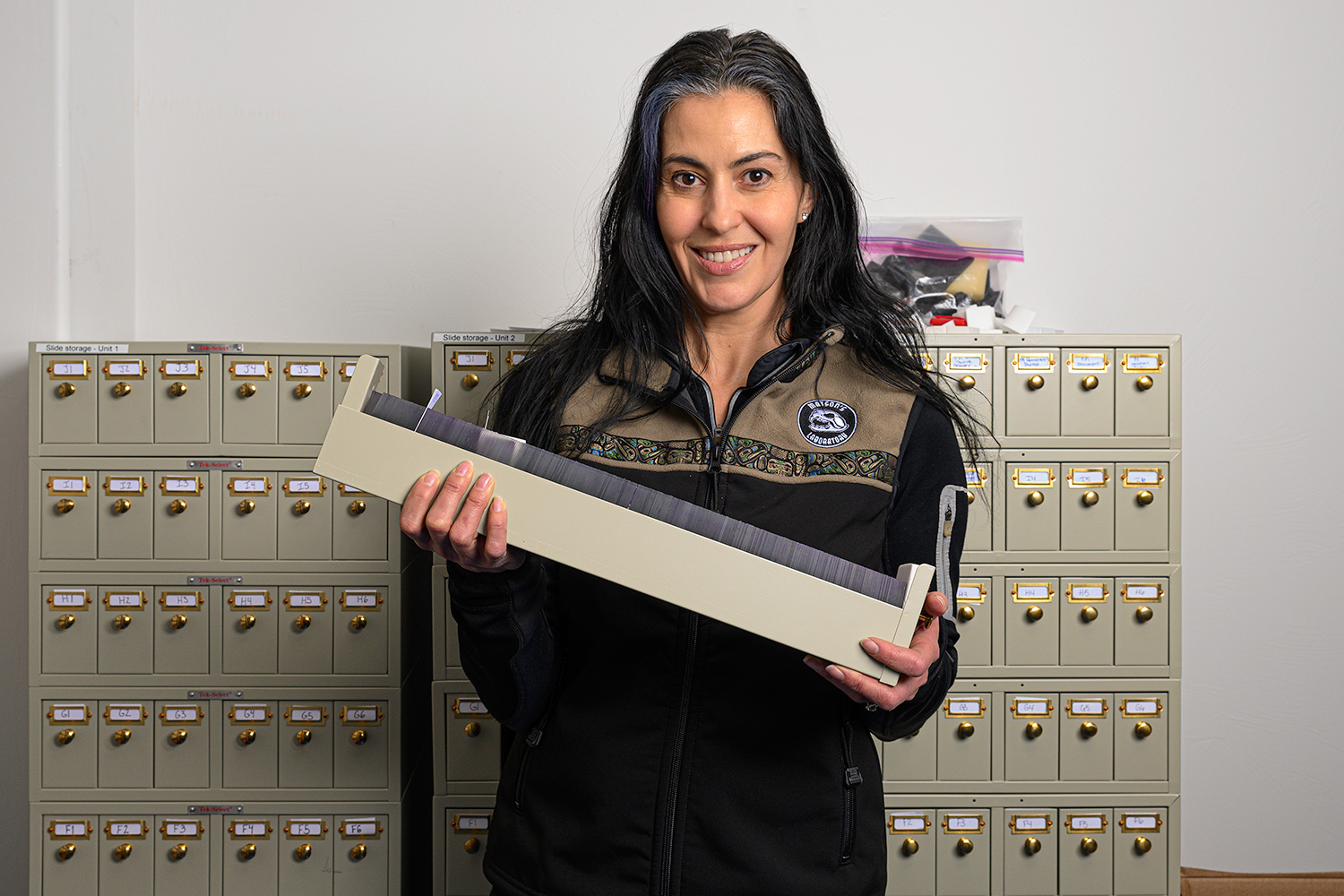 biologist carolyn nistler holds a tray containing slides with teeth mounted on them