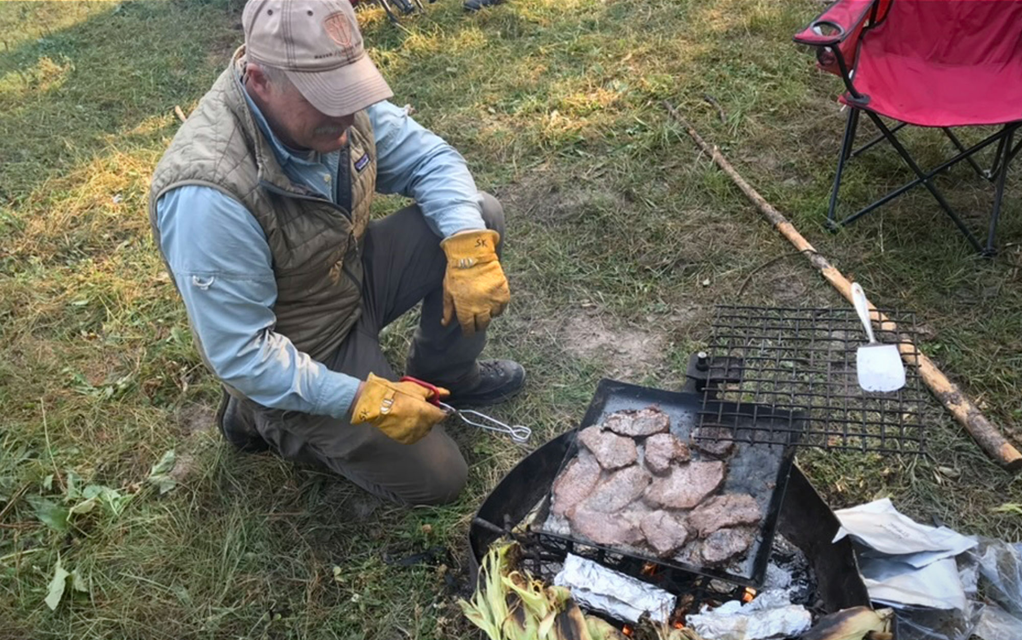 A backcountry horseman grills steaks.