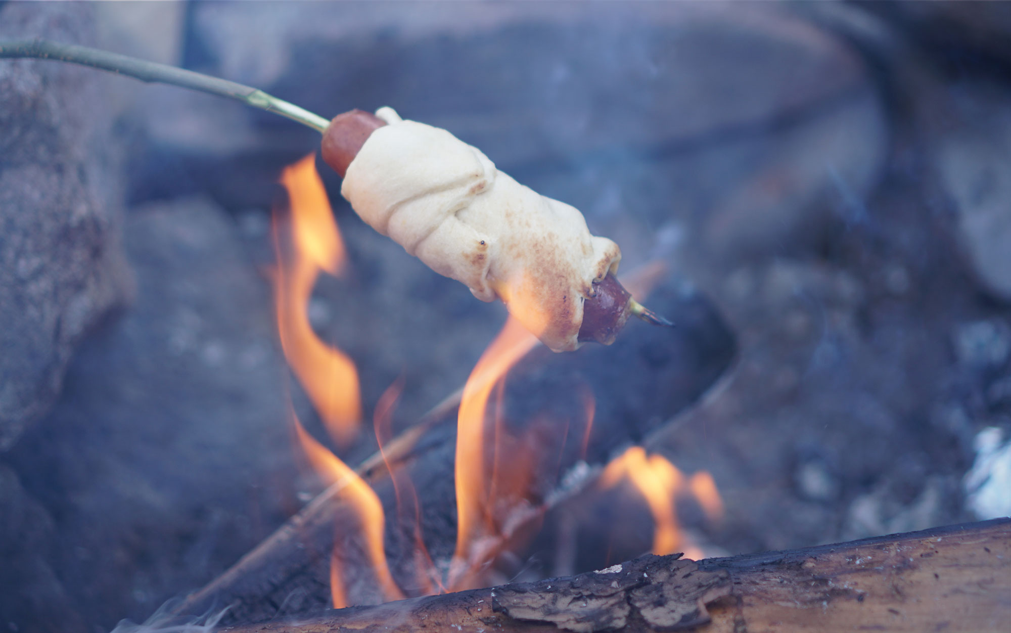 Roast bratwursts over coals.