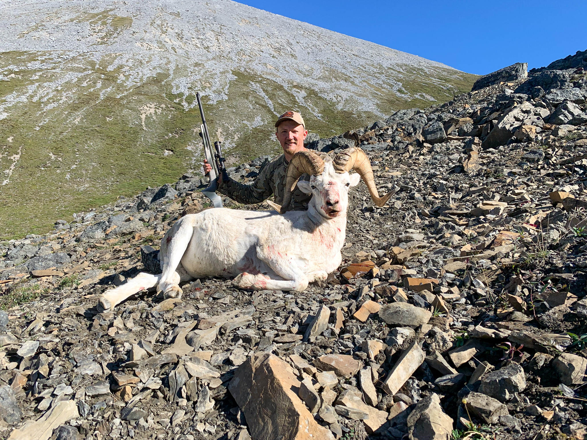 Sheep hunter Tyler Freel sits behind a full-curl Dall ram.