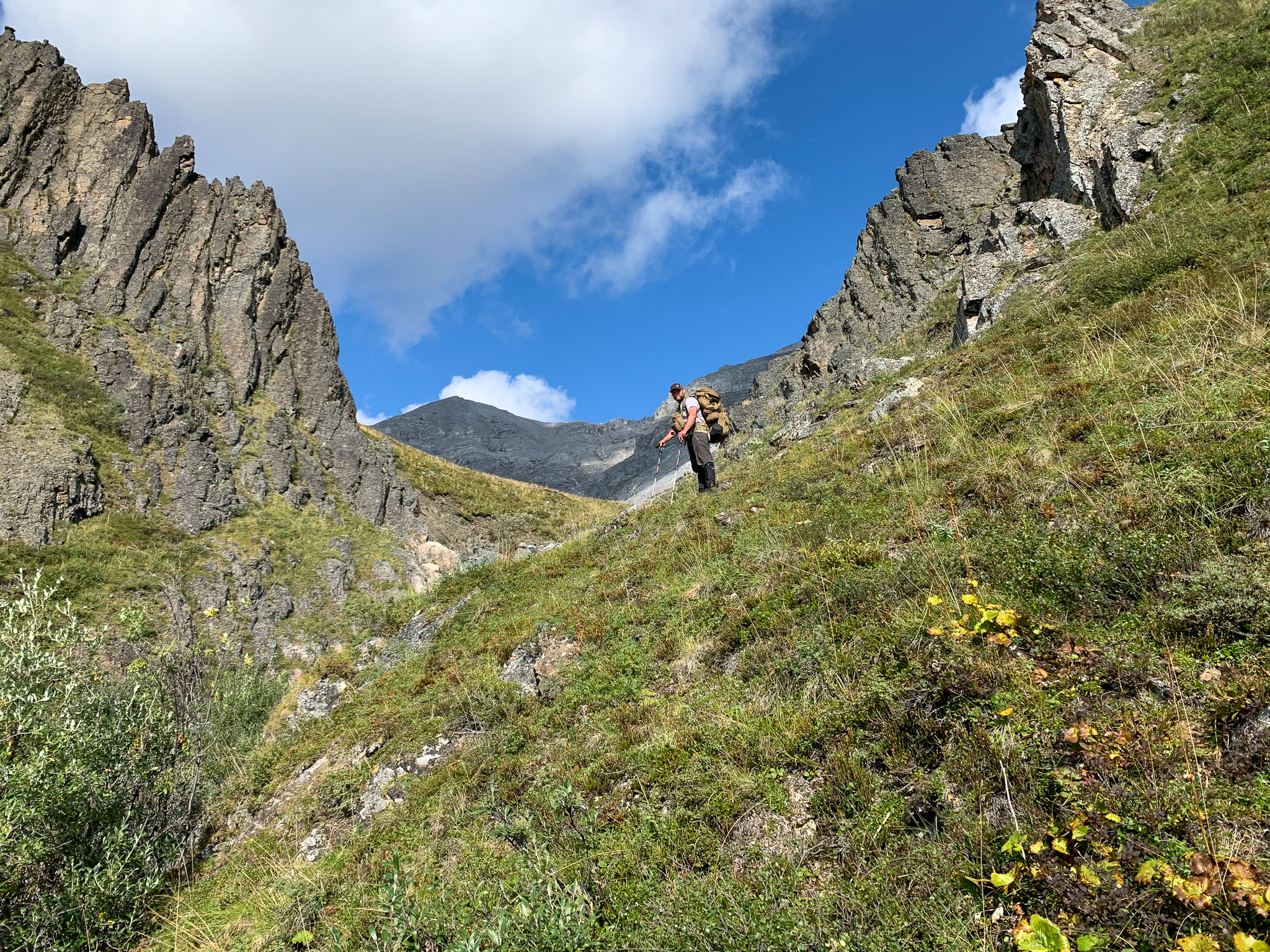 A hunter stands at the top of a steep mountain.