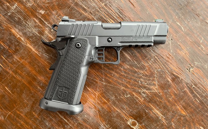 The MAC 9 1911DS, a silver gray semi-auto handgun on a wooden background.