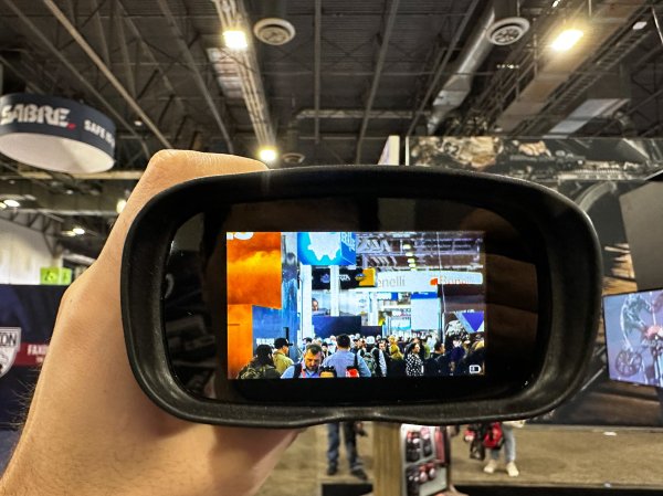 A pair of night-vision binoculars shows a showroom floor at SHOT Show 2024.