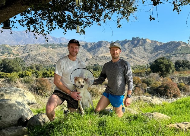 Two trail runners kneel next to a dog that was attacked by a mountain lion.