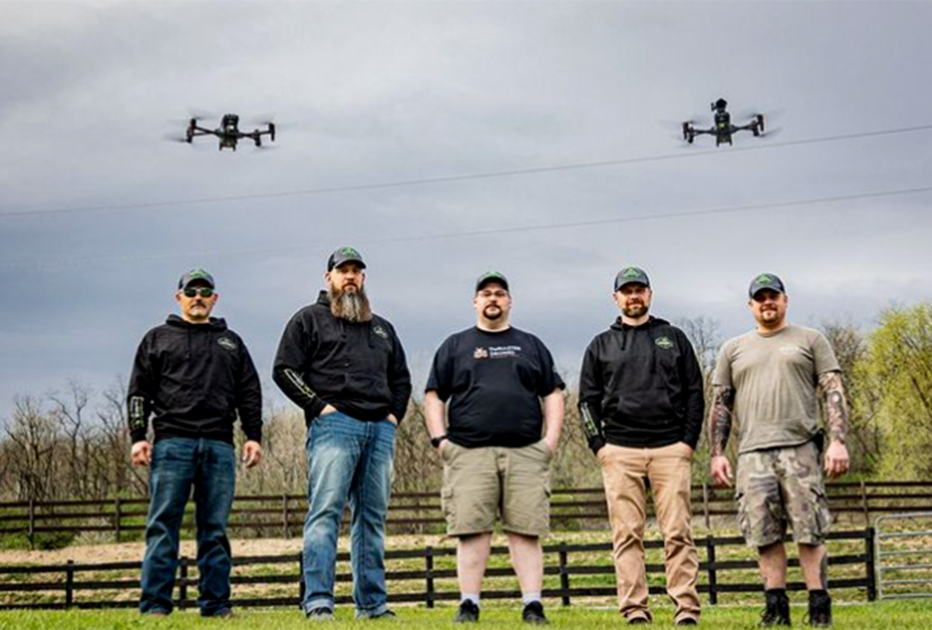 Five licensed drone pilots with drones flying overhead.