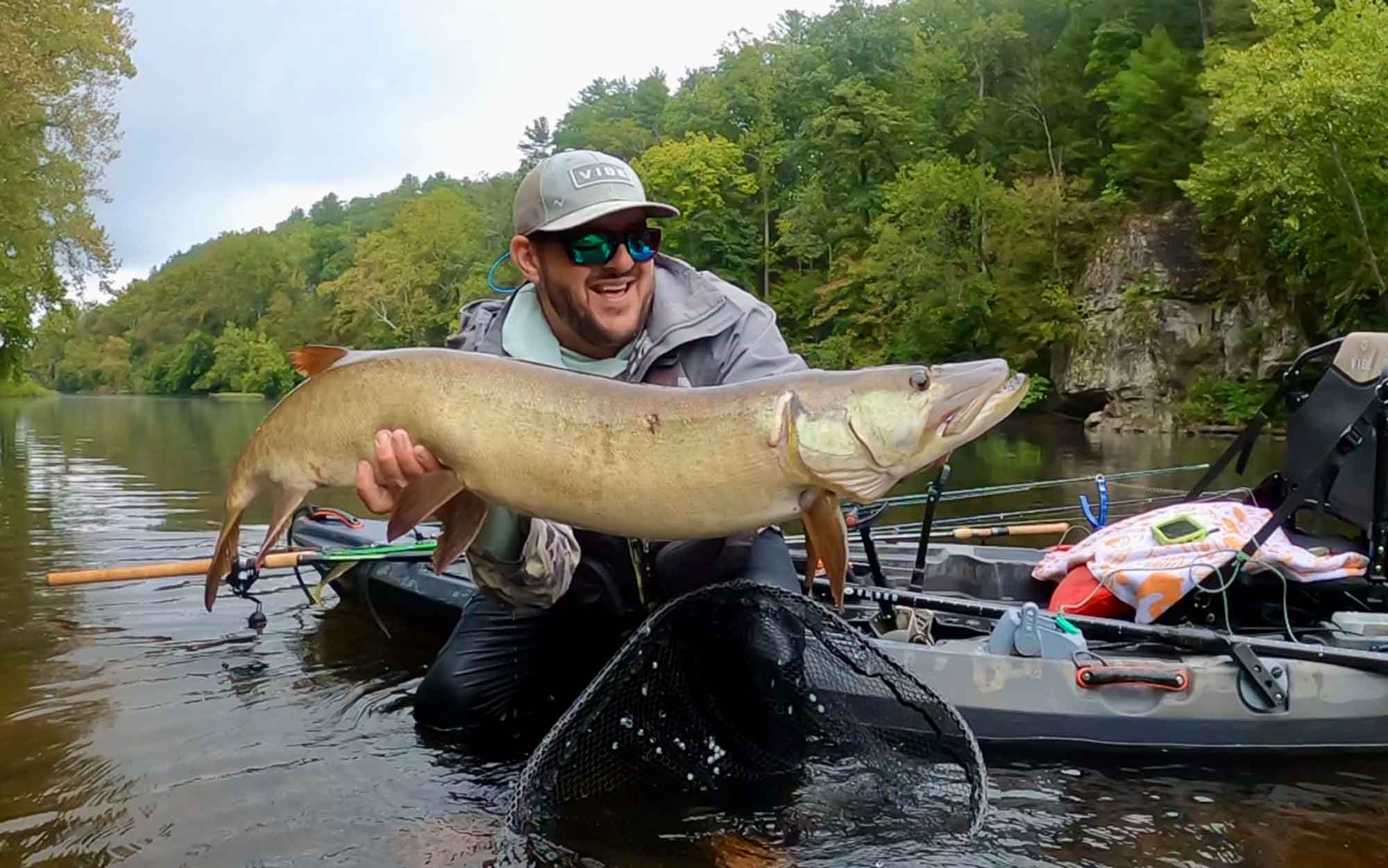 Author poses with fish in front of kayak.