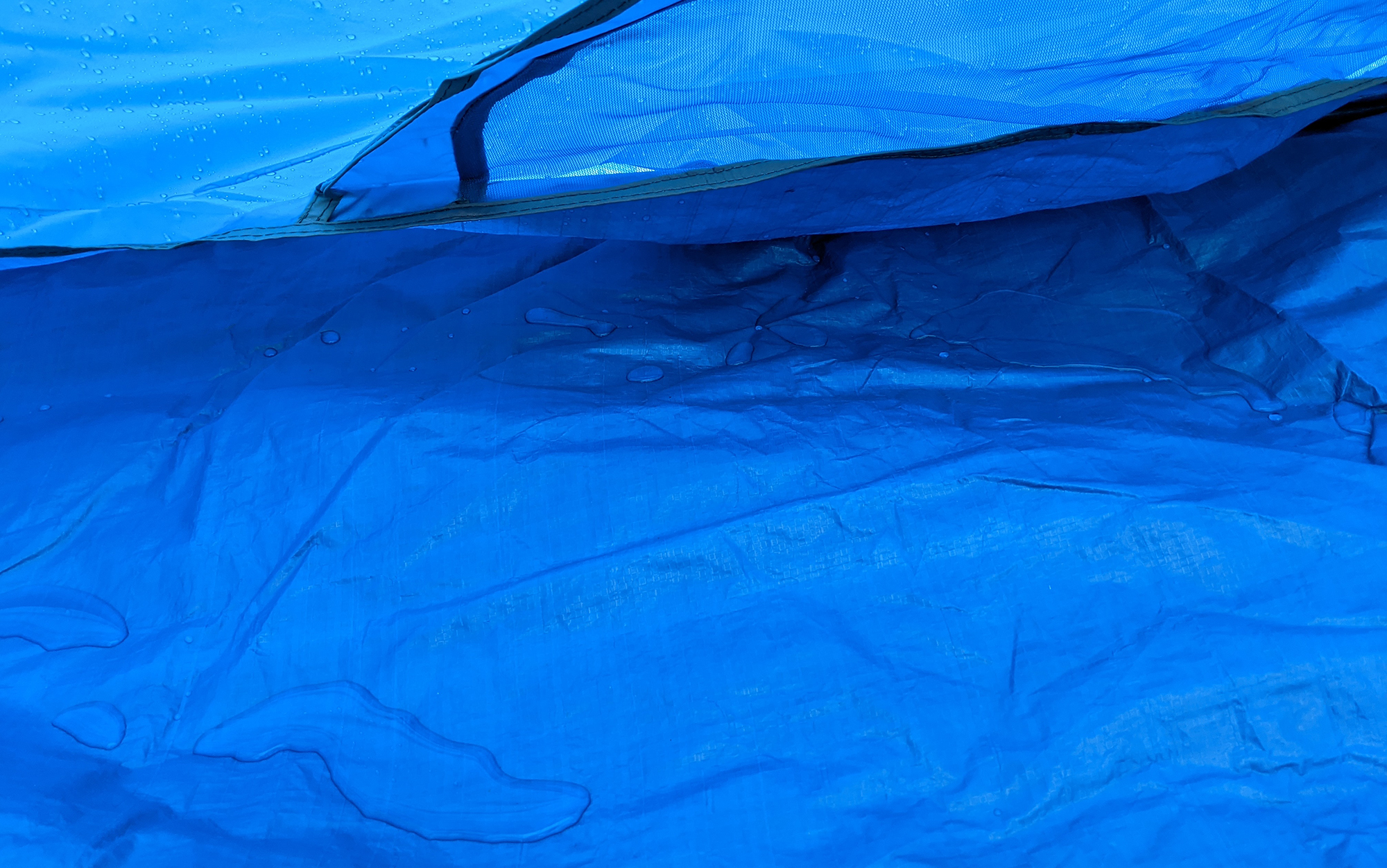 A water puddle pools in a tent corner.