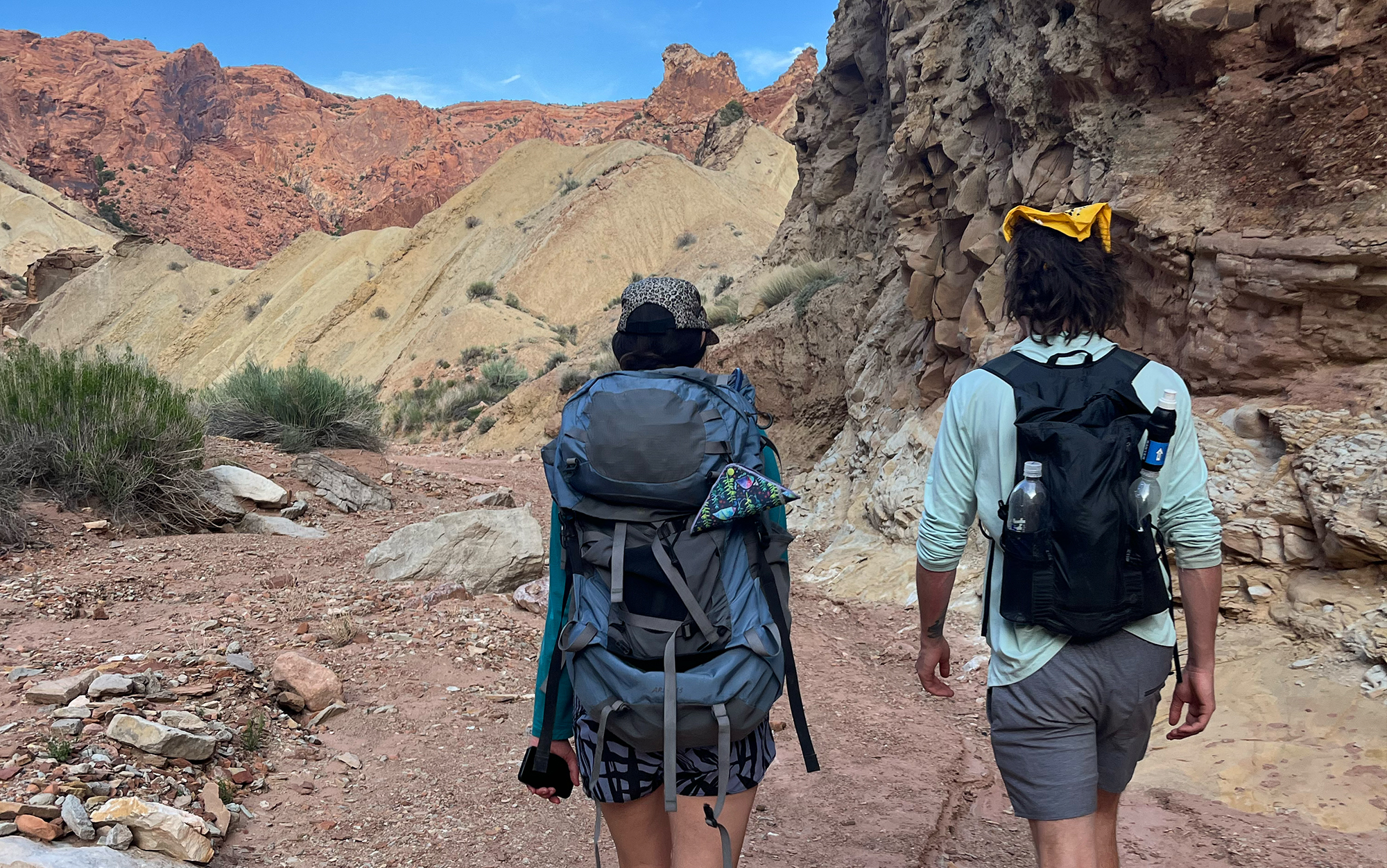 Two hikers walking in the desert with backpacks.