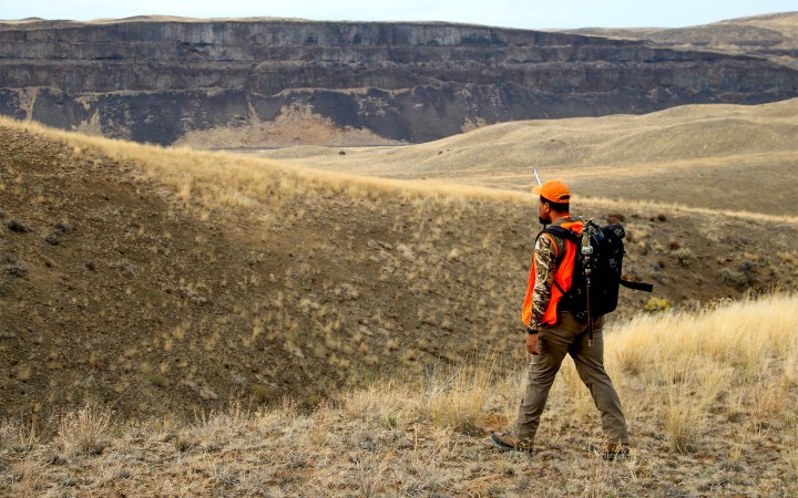 A lone hunter walks a ridge.