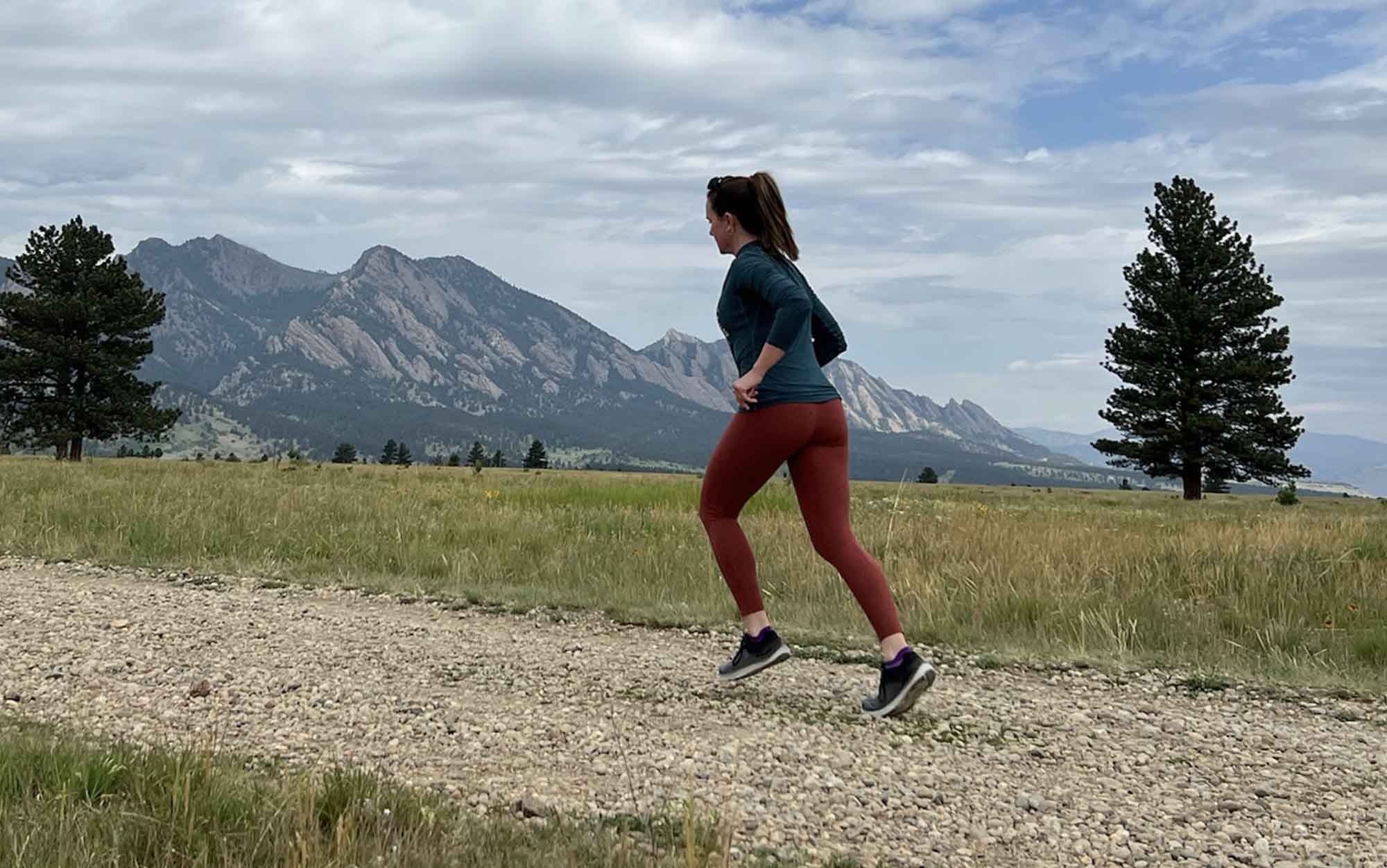 Woman running uphill in zero-drop running shoes Topo Magnifly