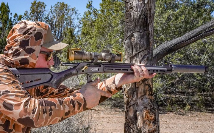 A man in a camo sun shirt and hood works the action of the Marlin Dark Series 1895 45-70