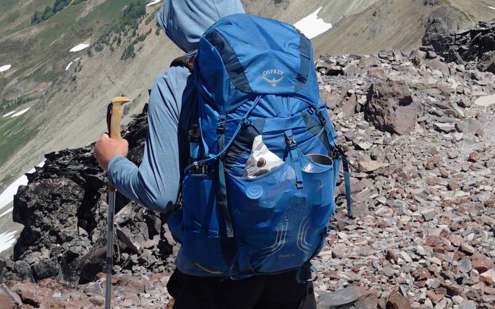  close up of Osprey backpack as man walks down a mountain ridge