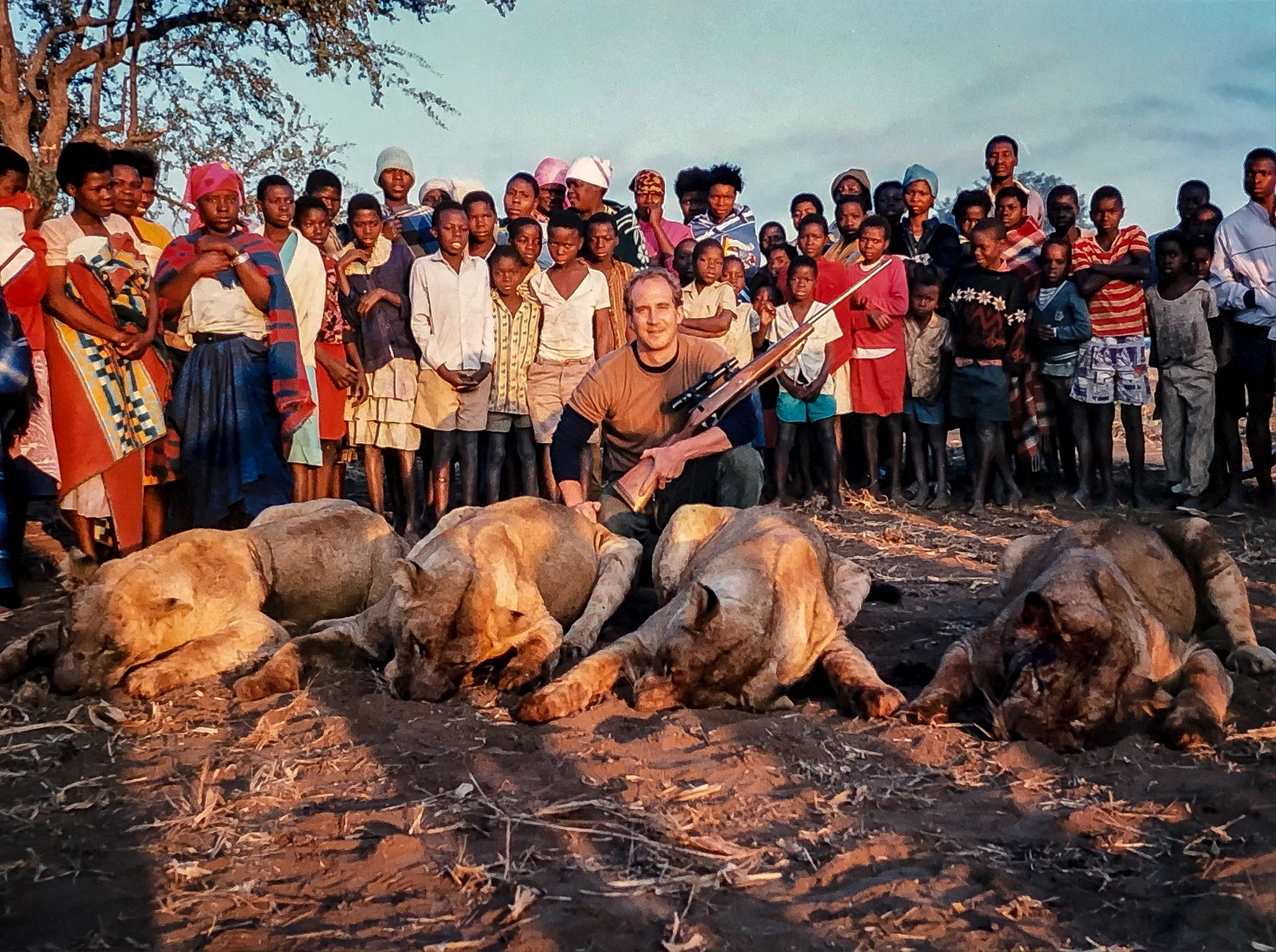 A village gathers around four dead maneating lions