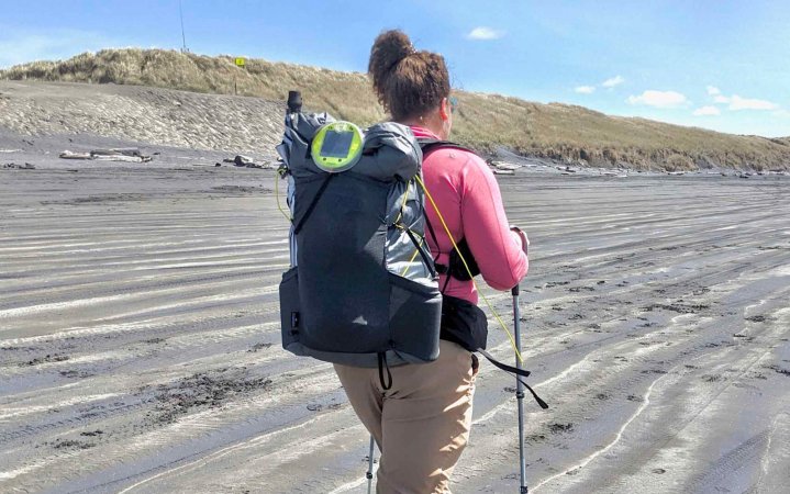  woman walking along beach wearing an SMD Swift X backpack