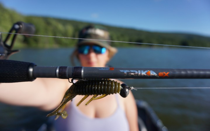 Angler holds up new Trika 6X rod on lake.