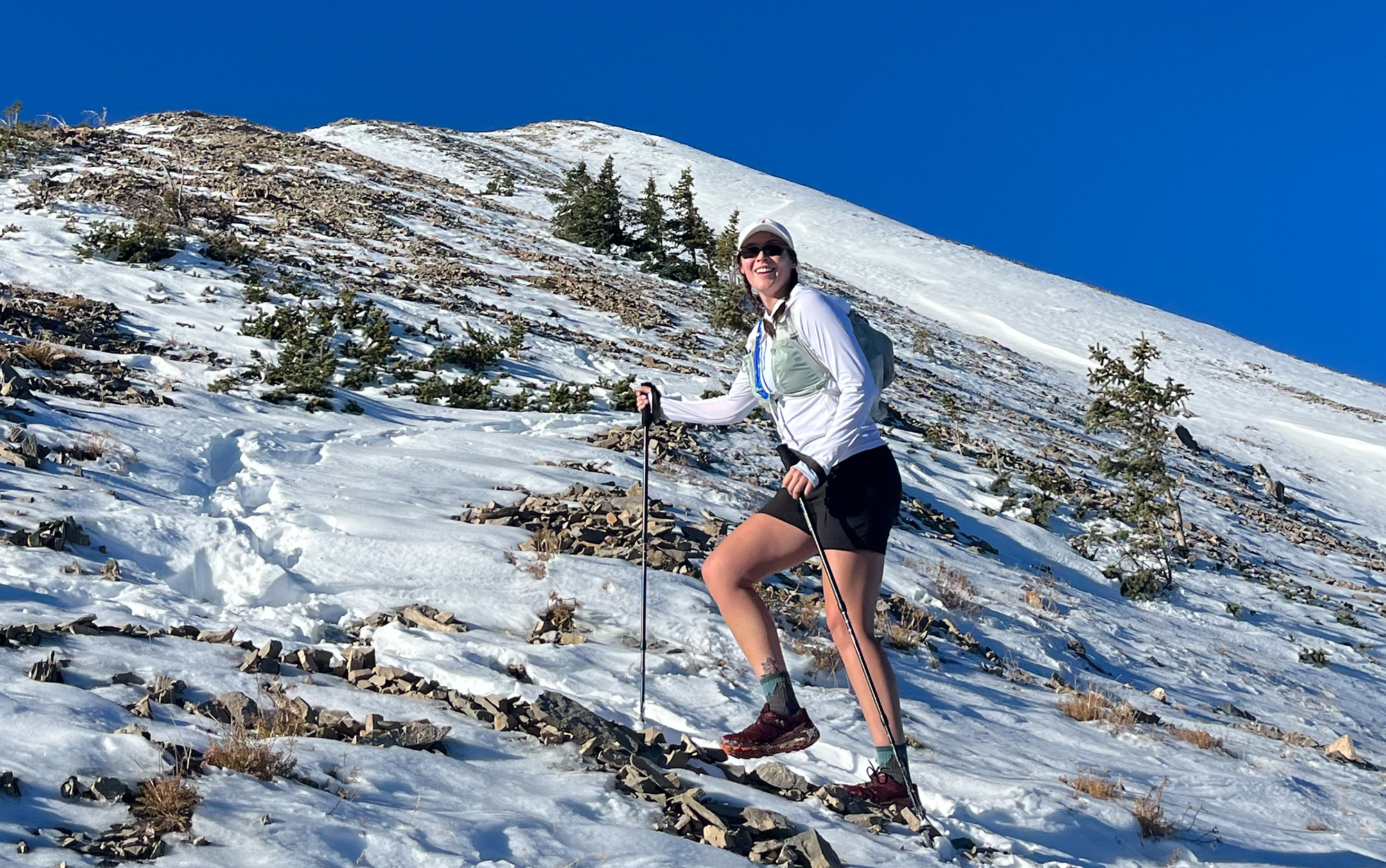 Author hikes snowy hill in running vest.