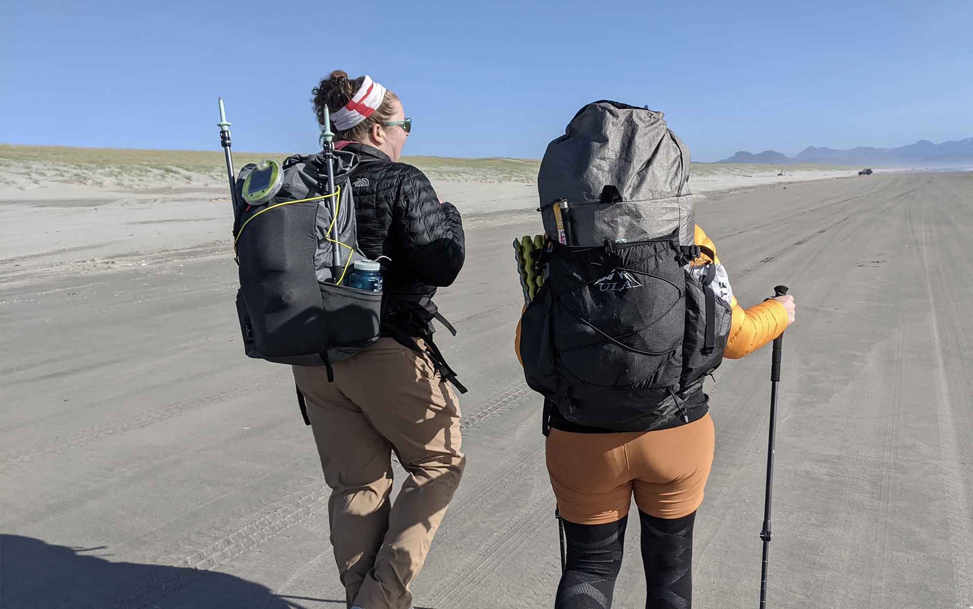 two woman backpacking along a beach using ultralight gear