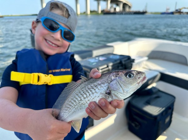 A kid holds up a croaker.