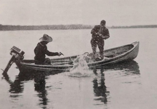 Man shoots muskie in old-school photo.