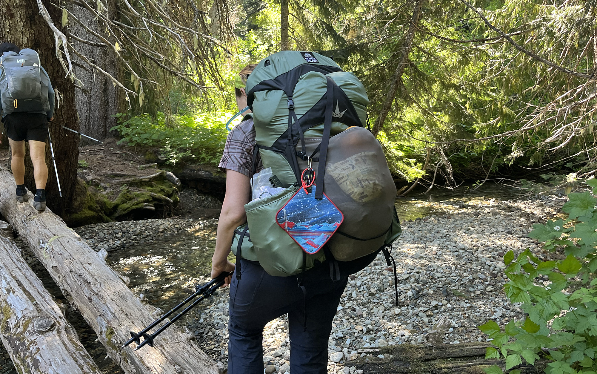 woman hiking across log with Granite Gear backpack