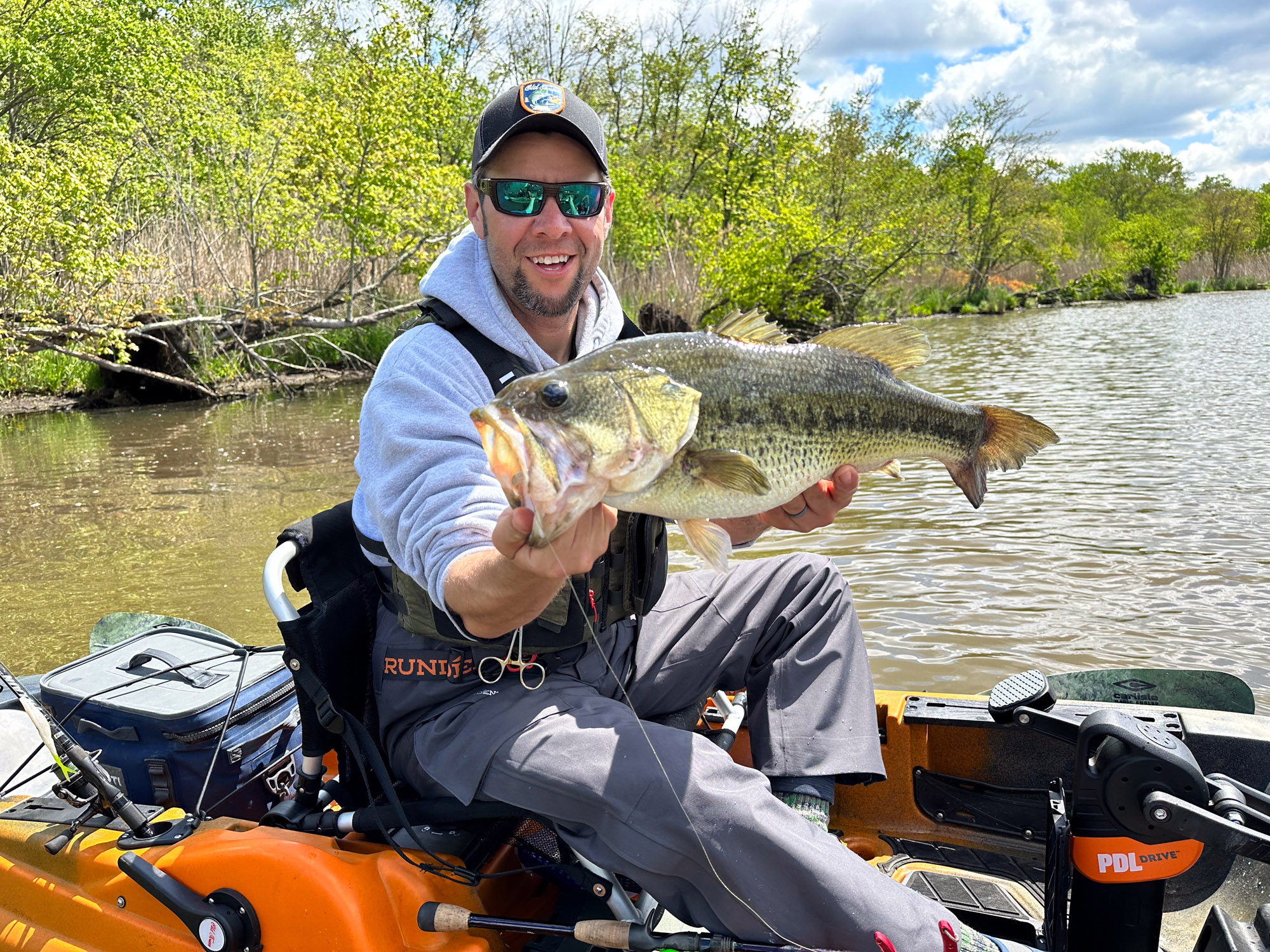 A kayak fisherman holds up a nice largemouth bass.