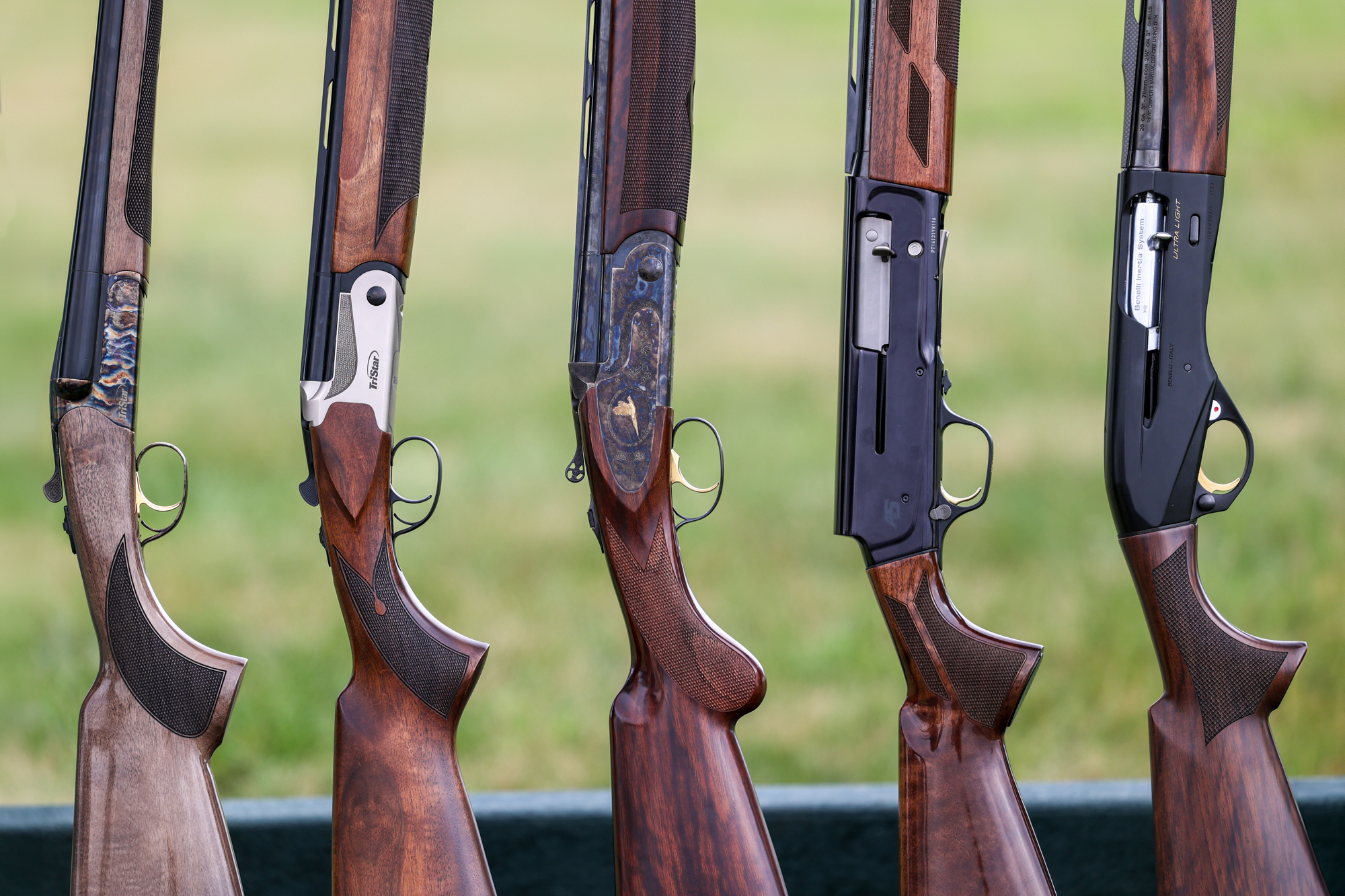 Five wood-stocked shotguns in a row.