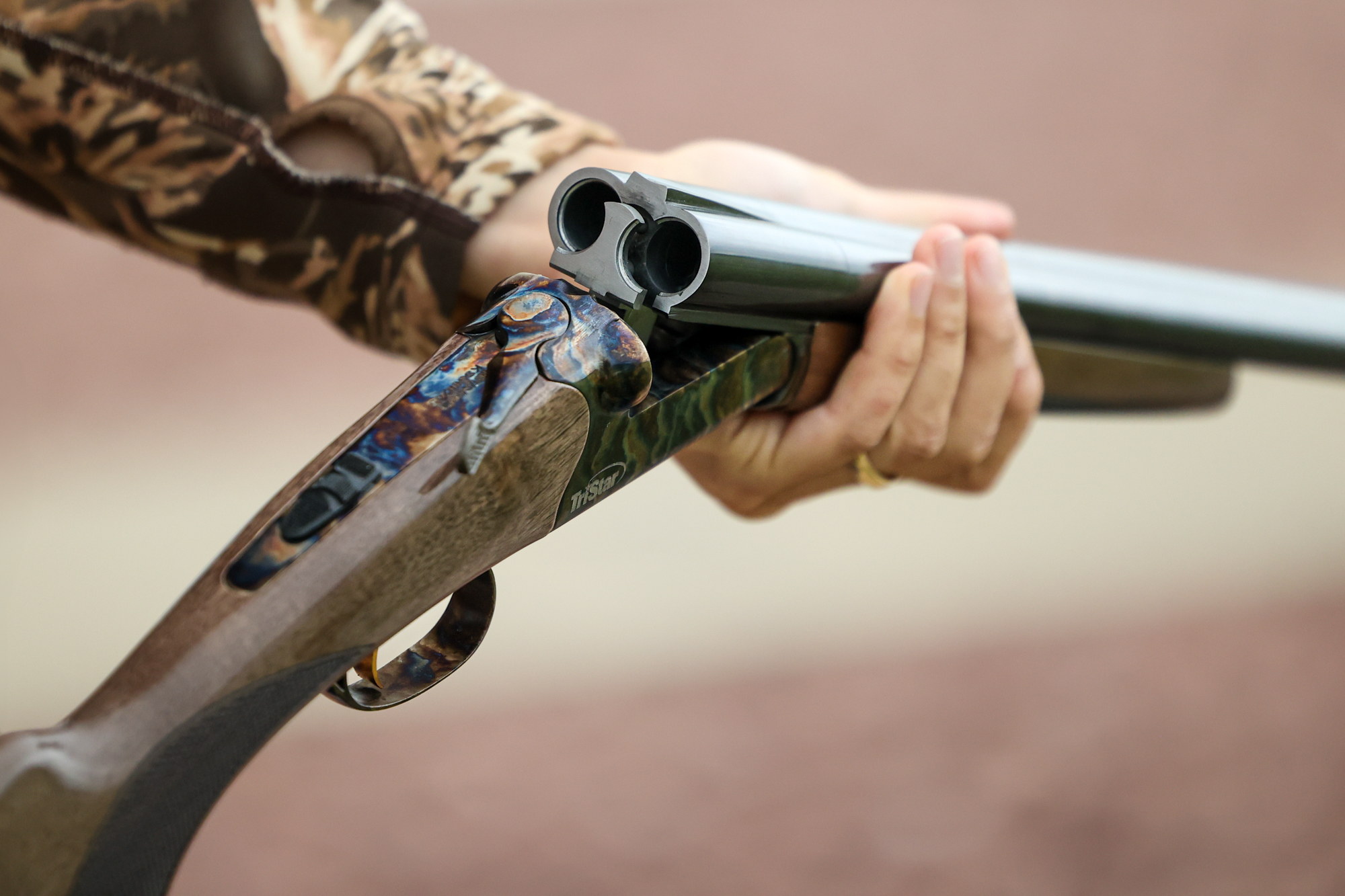 A side-by-side shotgun with its action cracked, in hand.