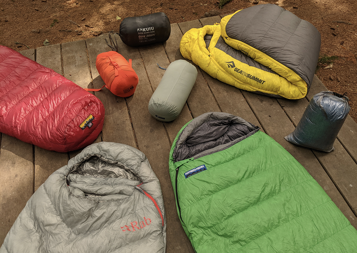 sleeping bags both unpacked and packed up on a wooden platform