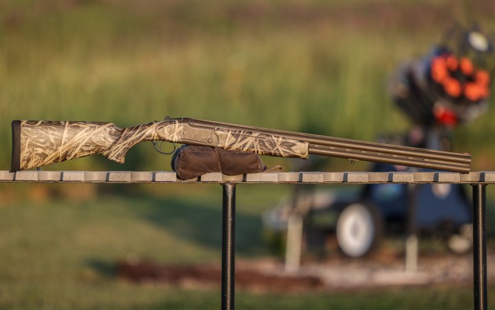  The Mossberg Eventide Waterfowl over/under shotgun rests on a shooting bag on a table.