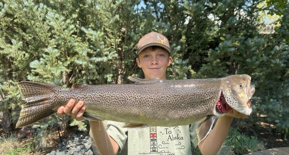 Teen holds up large tiger trout.