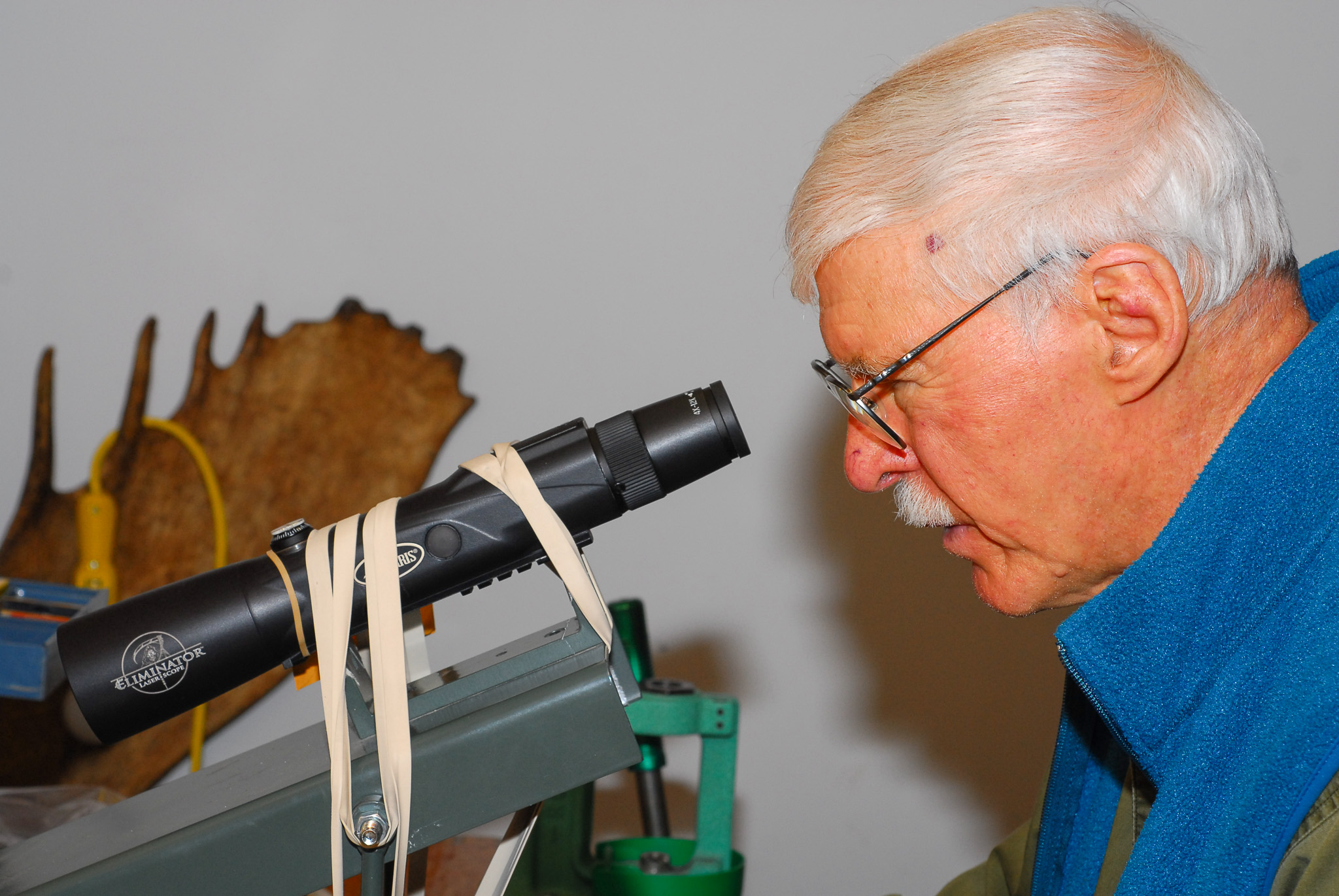 A man looks at a riflescope.