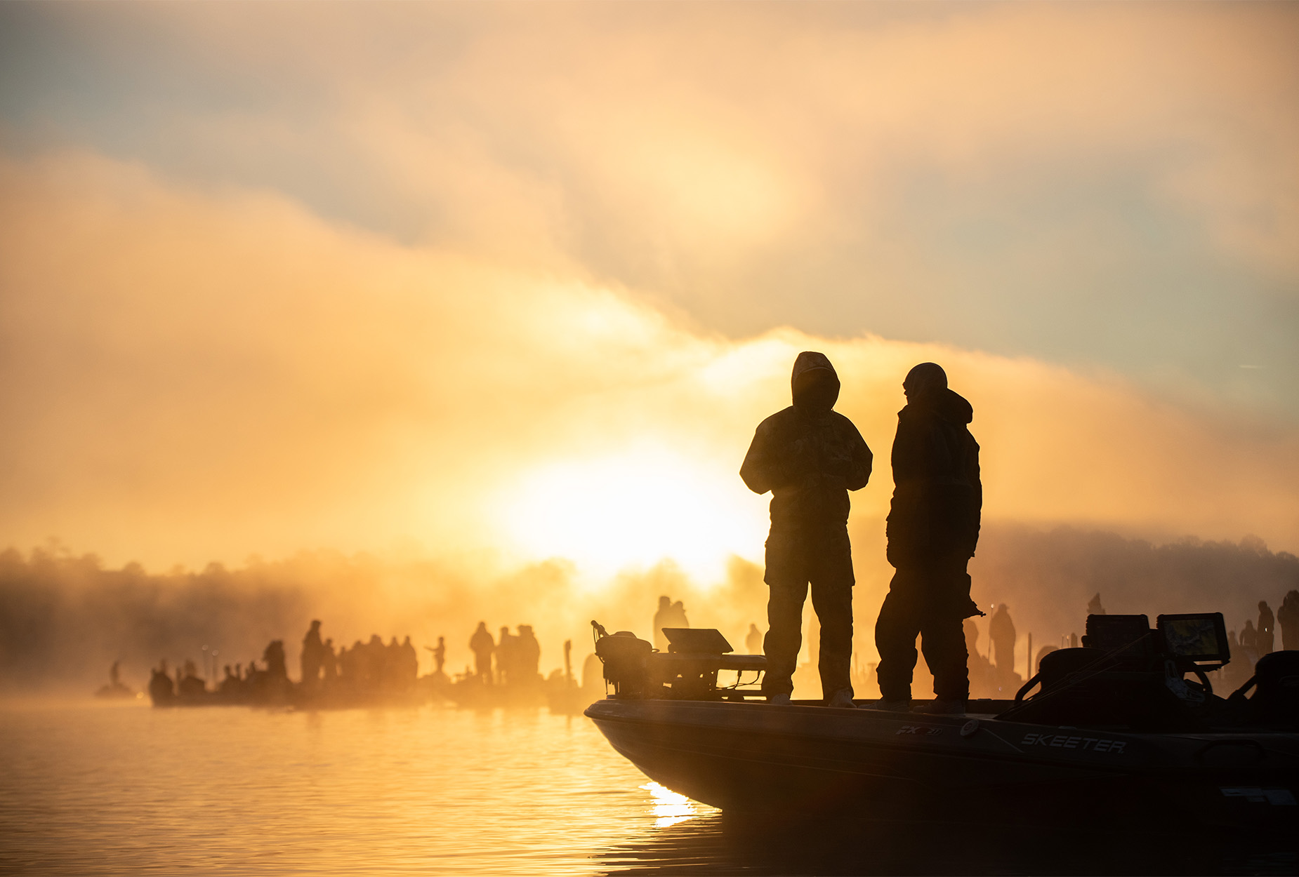 Two anglers on a boat at sunrise.