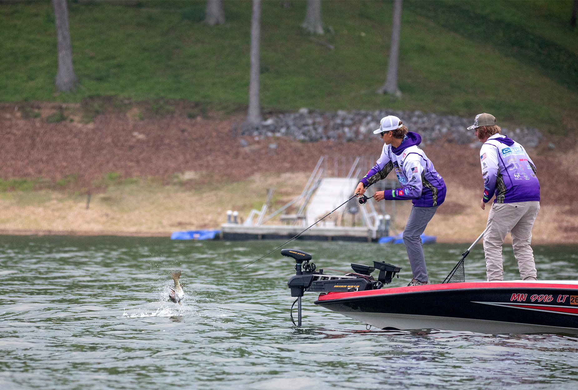 An angler hooks a bass from the bow.