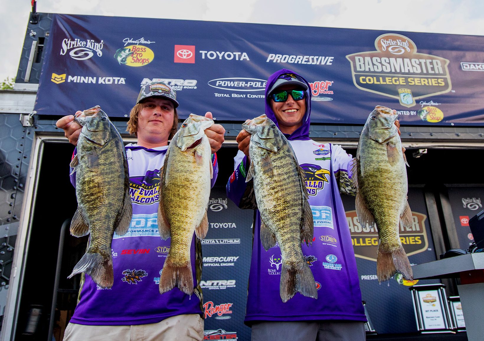 Two college anglers hold up bass.