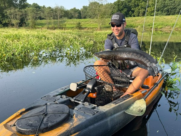 A kayak fisherman holds up a nice snakehead.