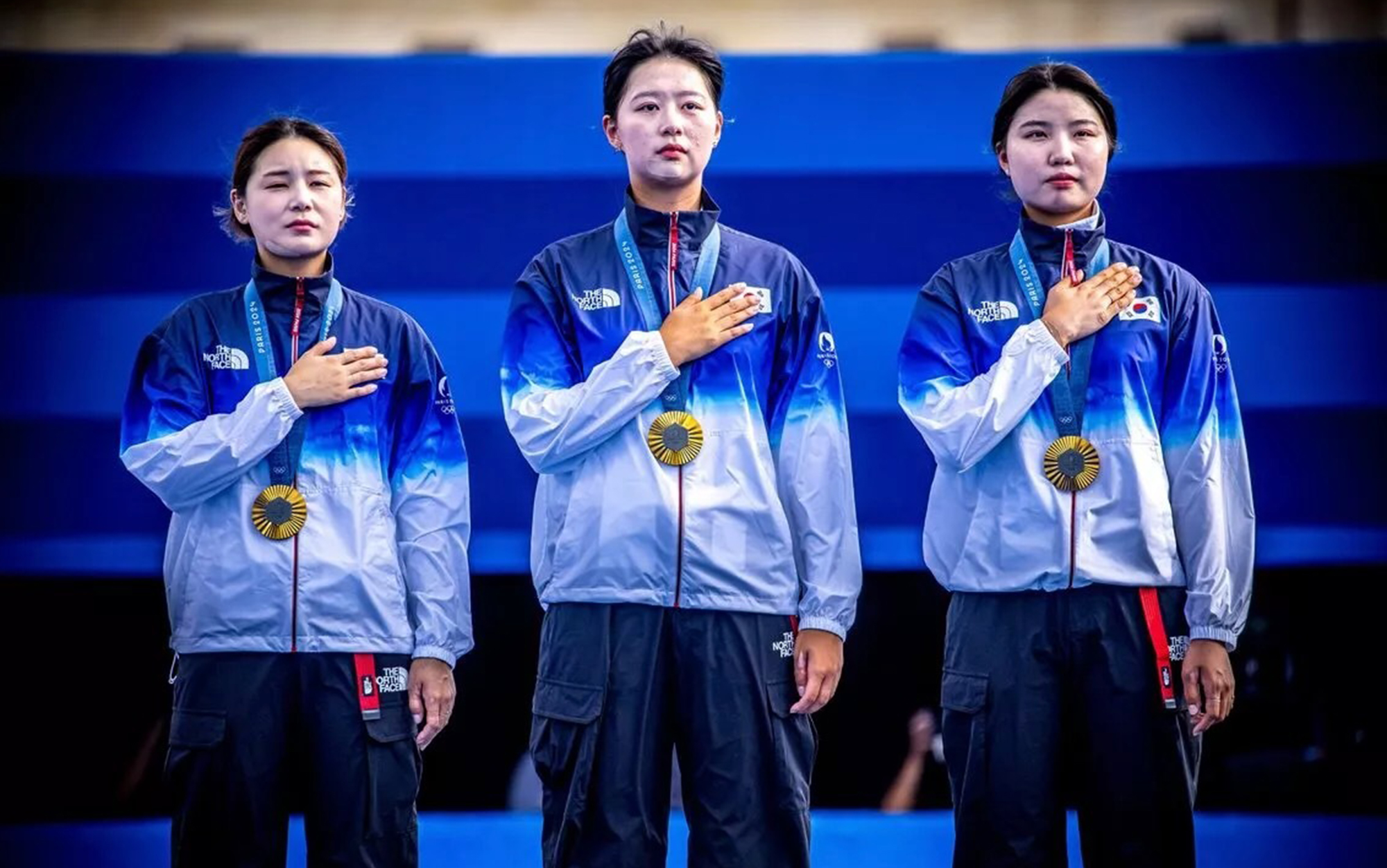 The Korean archery team stands at the podium.