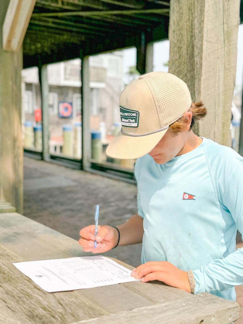 A kid fills out a form at a marina.