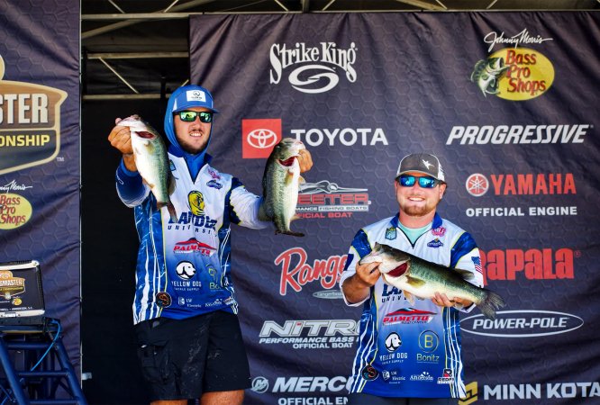 Two college fishermen hold up bass at a Bassmaster tournament.