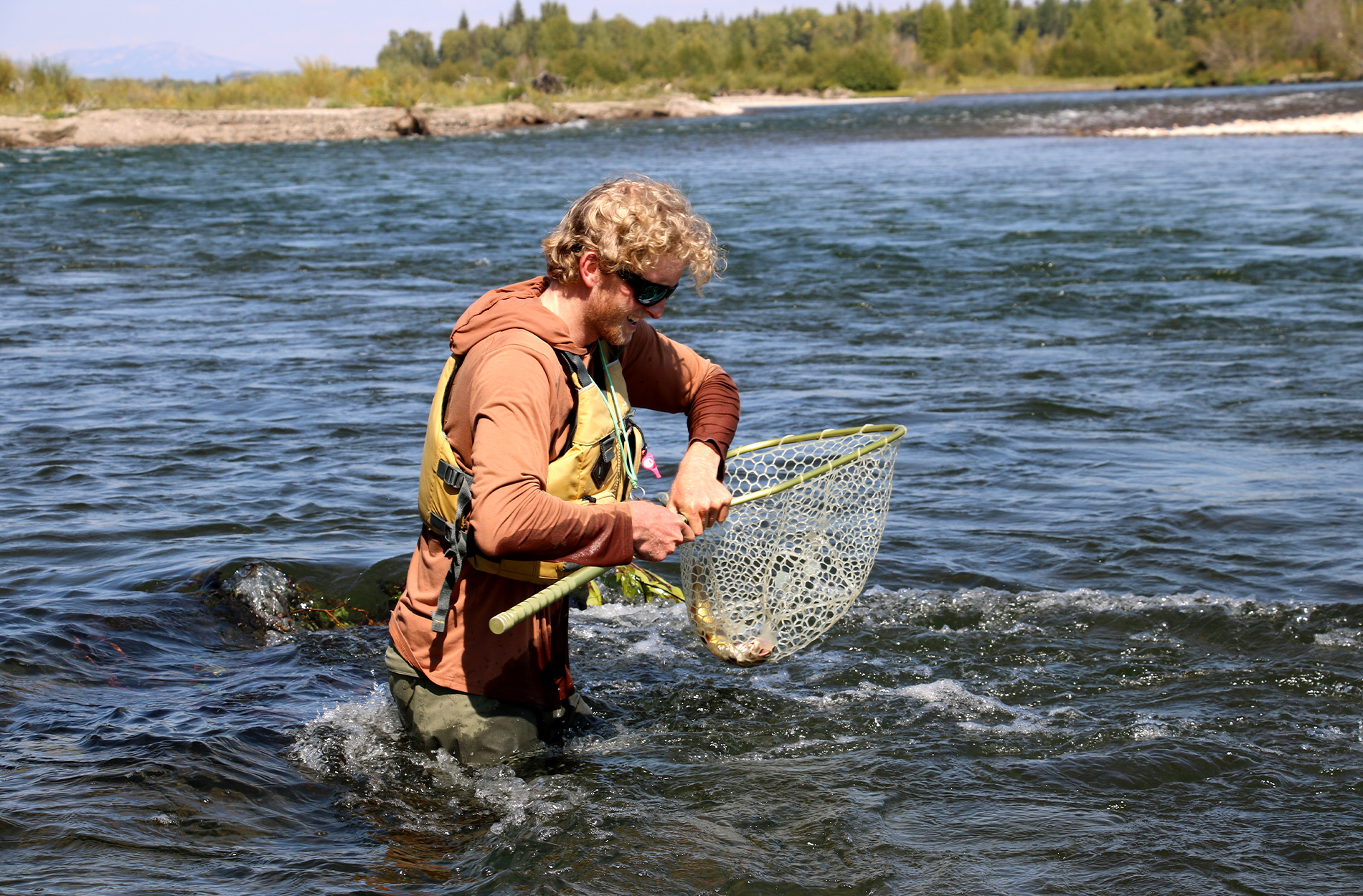 A guide smiles after netting a trout.