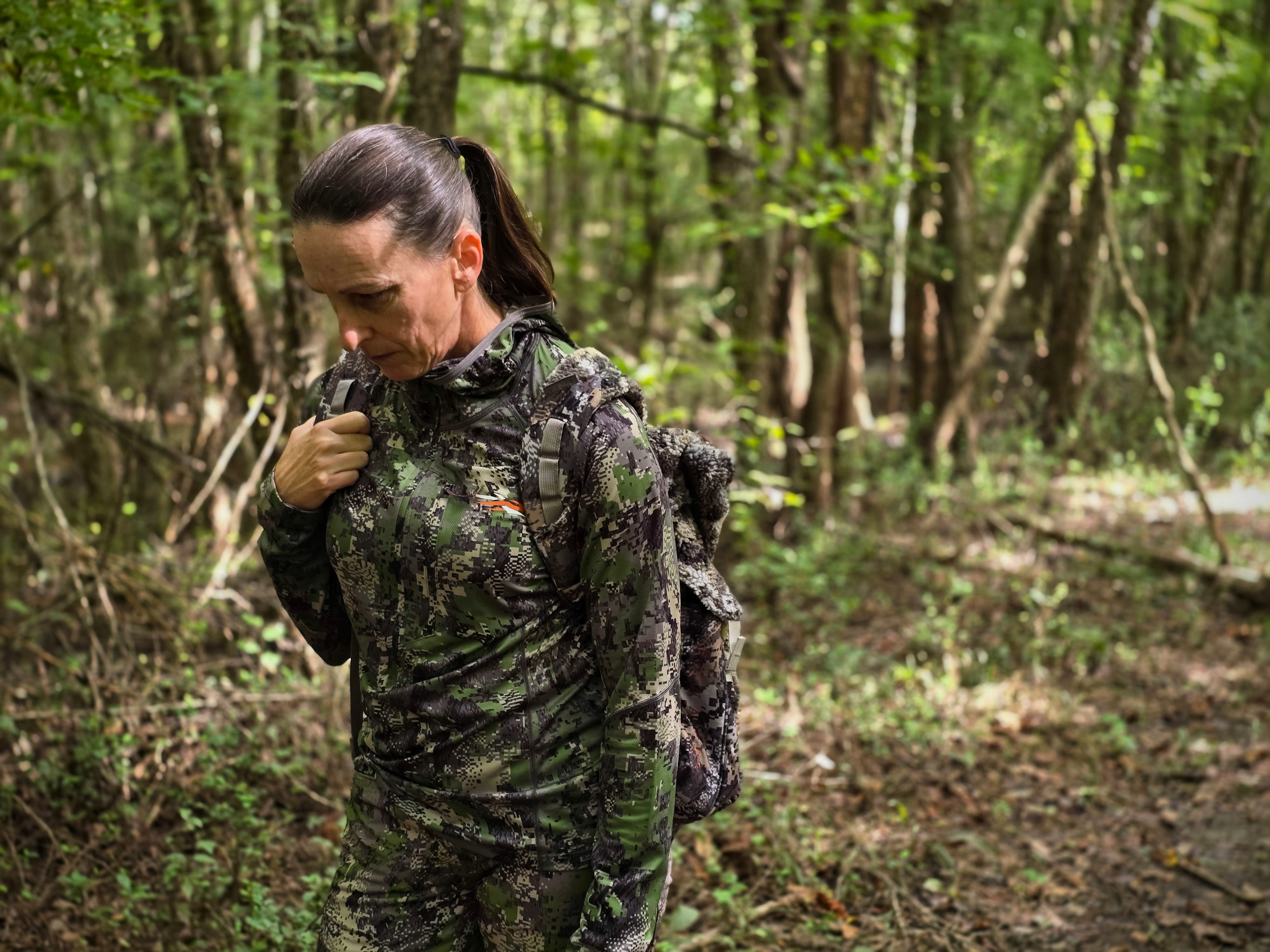 Female hunter in camo walks through the woods