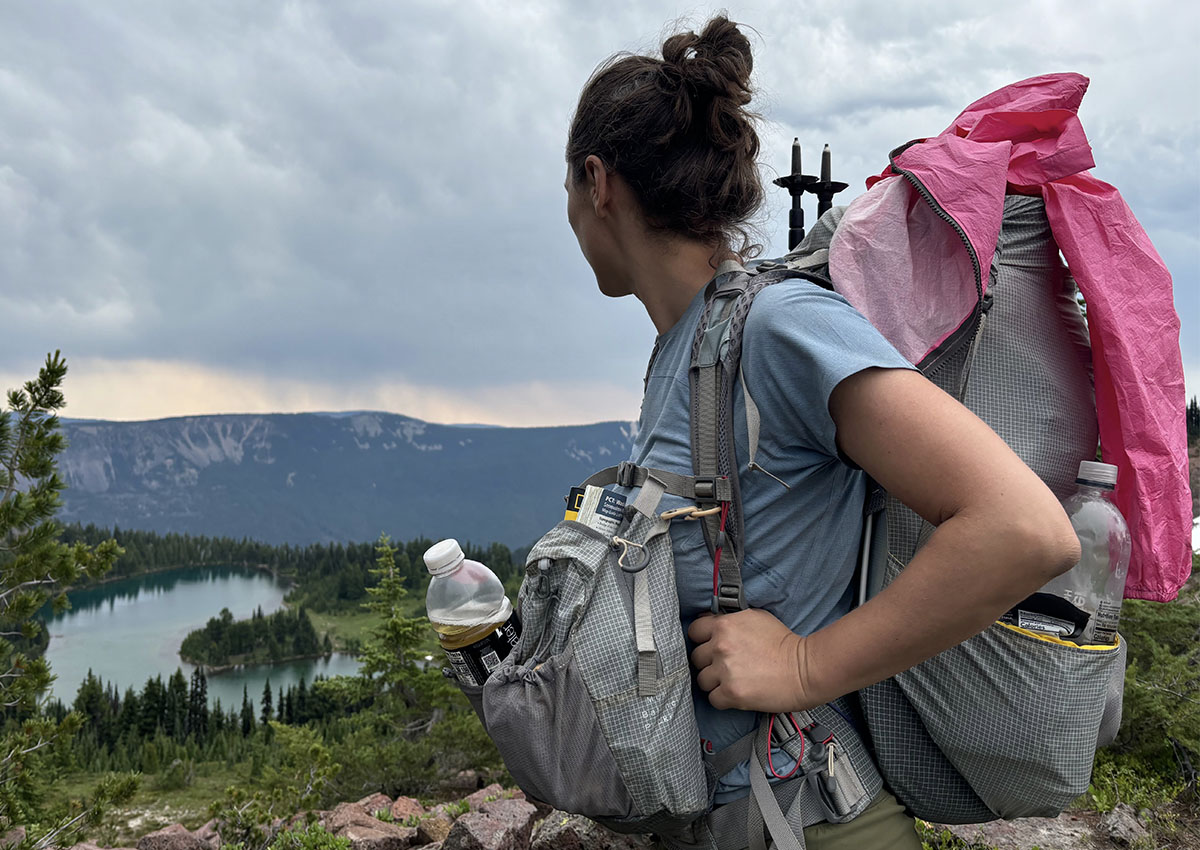 Woman wearing the Aarn Mountain Magic 50 Pro with an alpine lake in the background