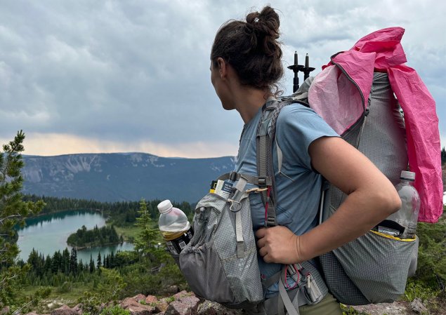 Woman wearing the Aarn Mountain Magic 50 Pro with an alpine lake in the background