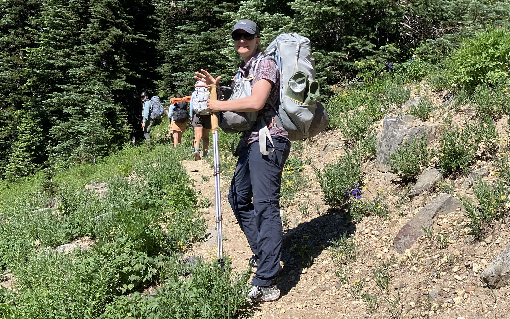 woman wearing the Aarn Mountain Magic 50 Pro on a mountain trail with two other hikers in the background