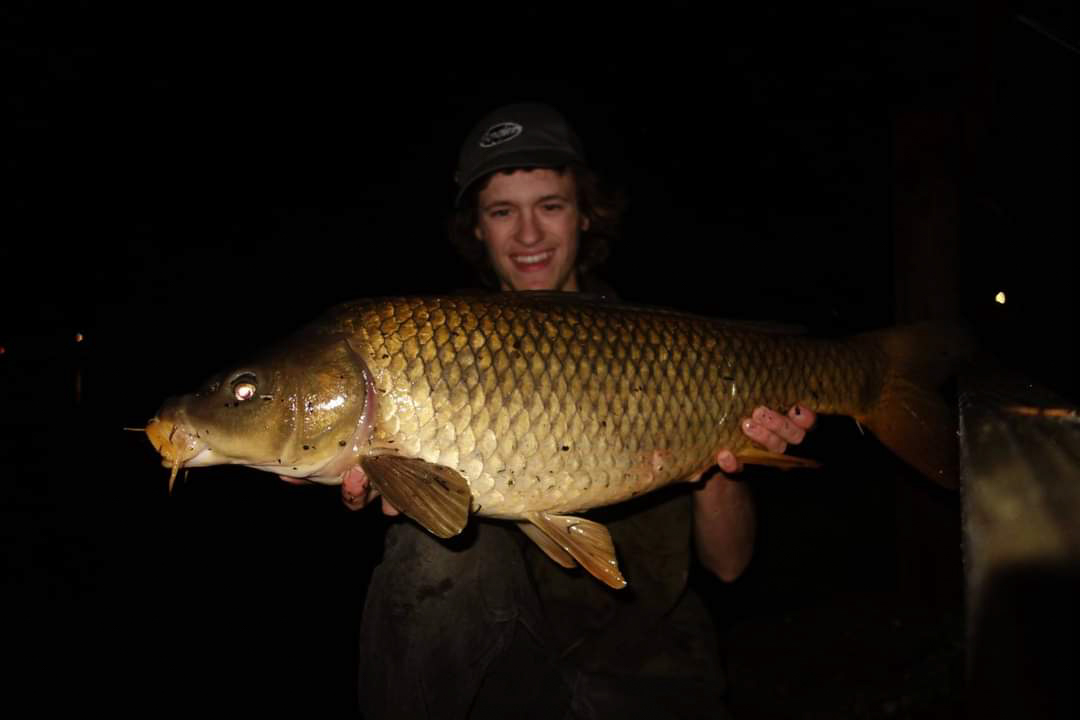 A fisherman in the dark with a big carp.