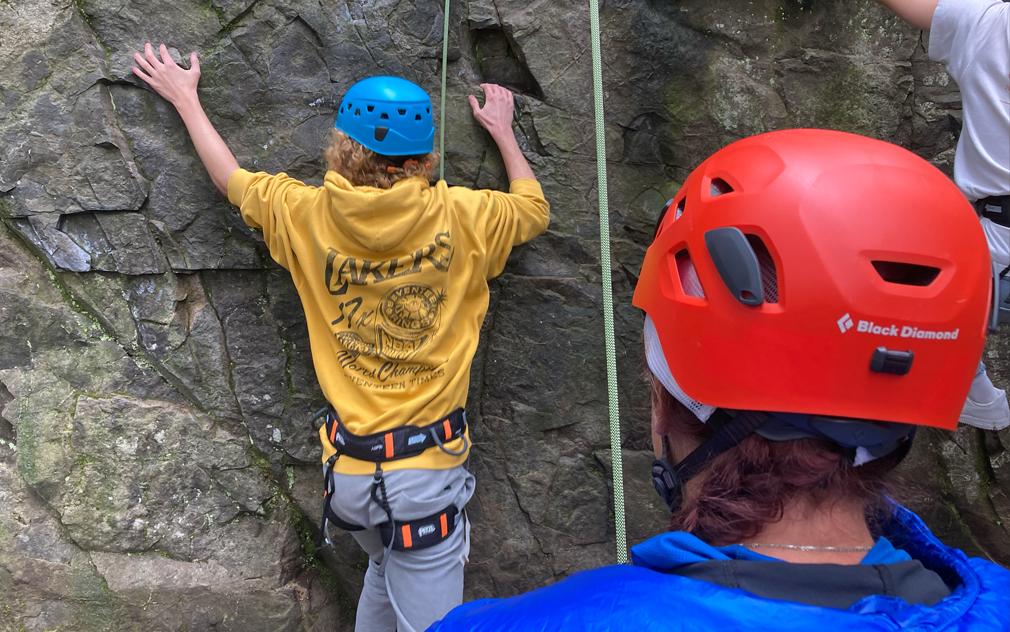 Climbers wear helmets at an outdoor rock wall.