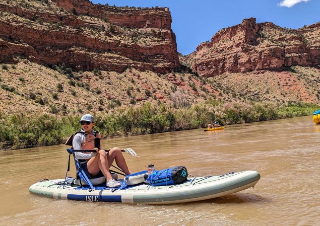 Woman sitting on a paddle board in the middle of the Colorado River