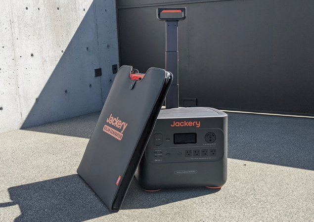 Jackery portable power station with folded-up solar panel leaning against it in driveway