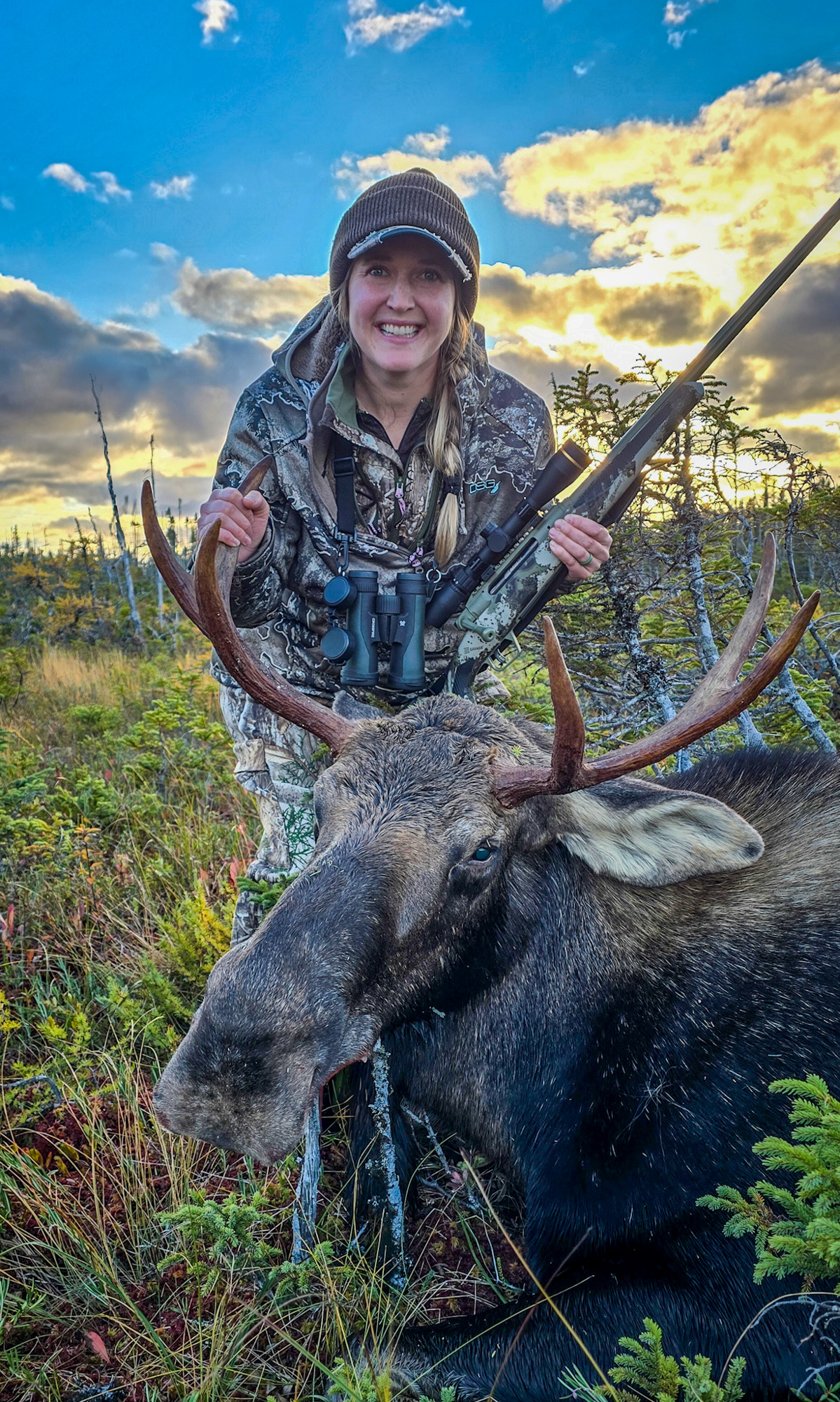 A woman holds a moose by the antlers.